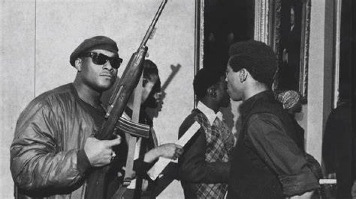 Black Panthers exiting building armed with rifles.