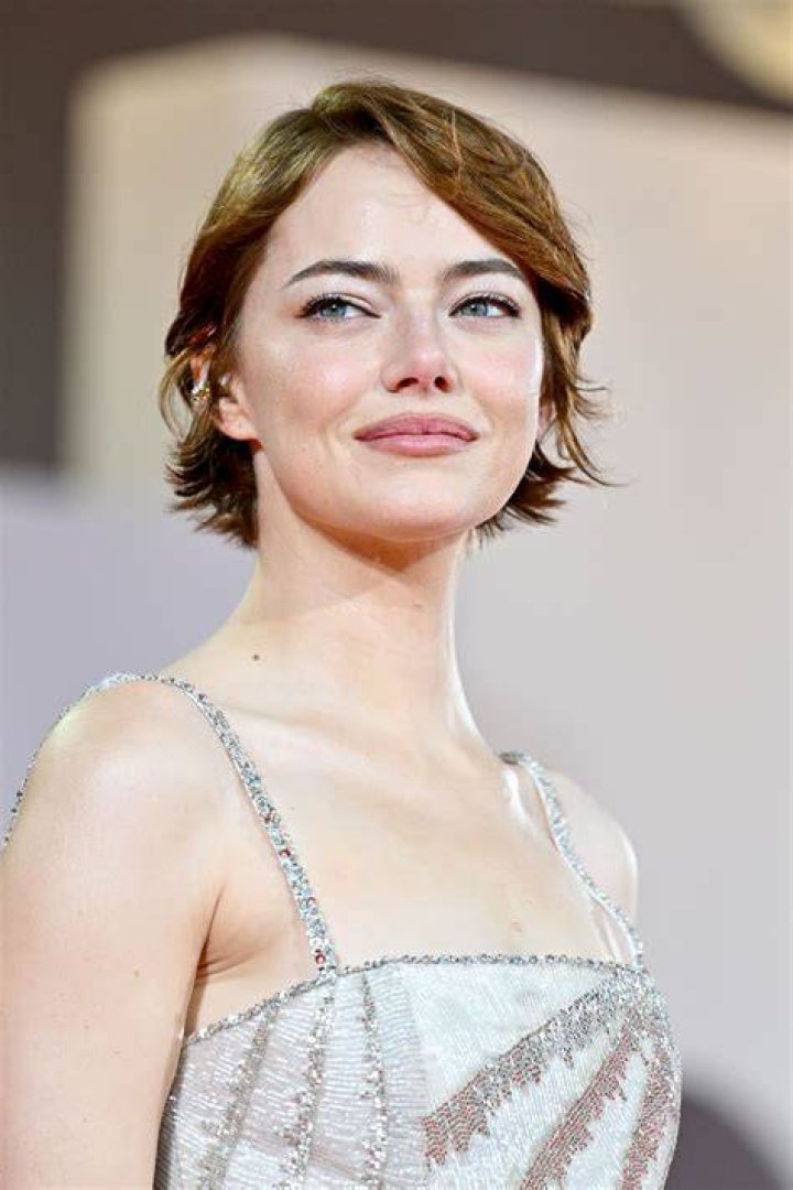 Emma Stone posing in a black and white suit.