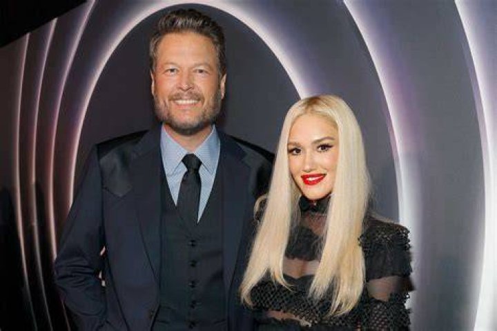 Gwen Stefani and Blake Shelton sitting next to each other and smiling for a photo