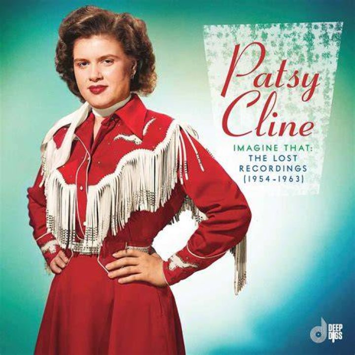 Patsy Cline poses leaned on a stack of pillows in a blue dress
