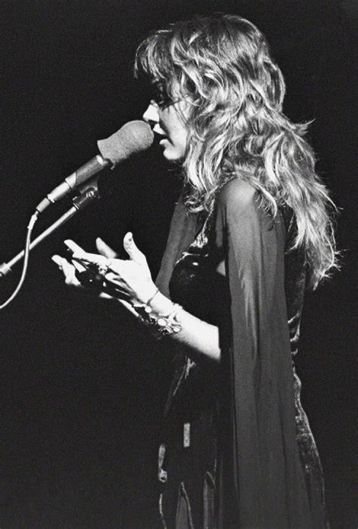 Stevie Nicks performs on stage wearing a shawl.